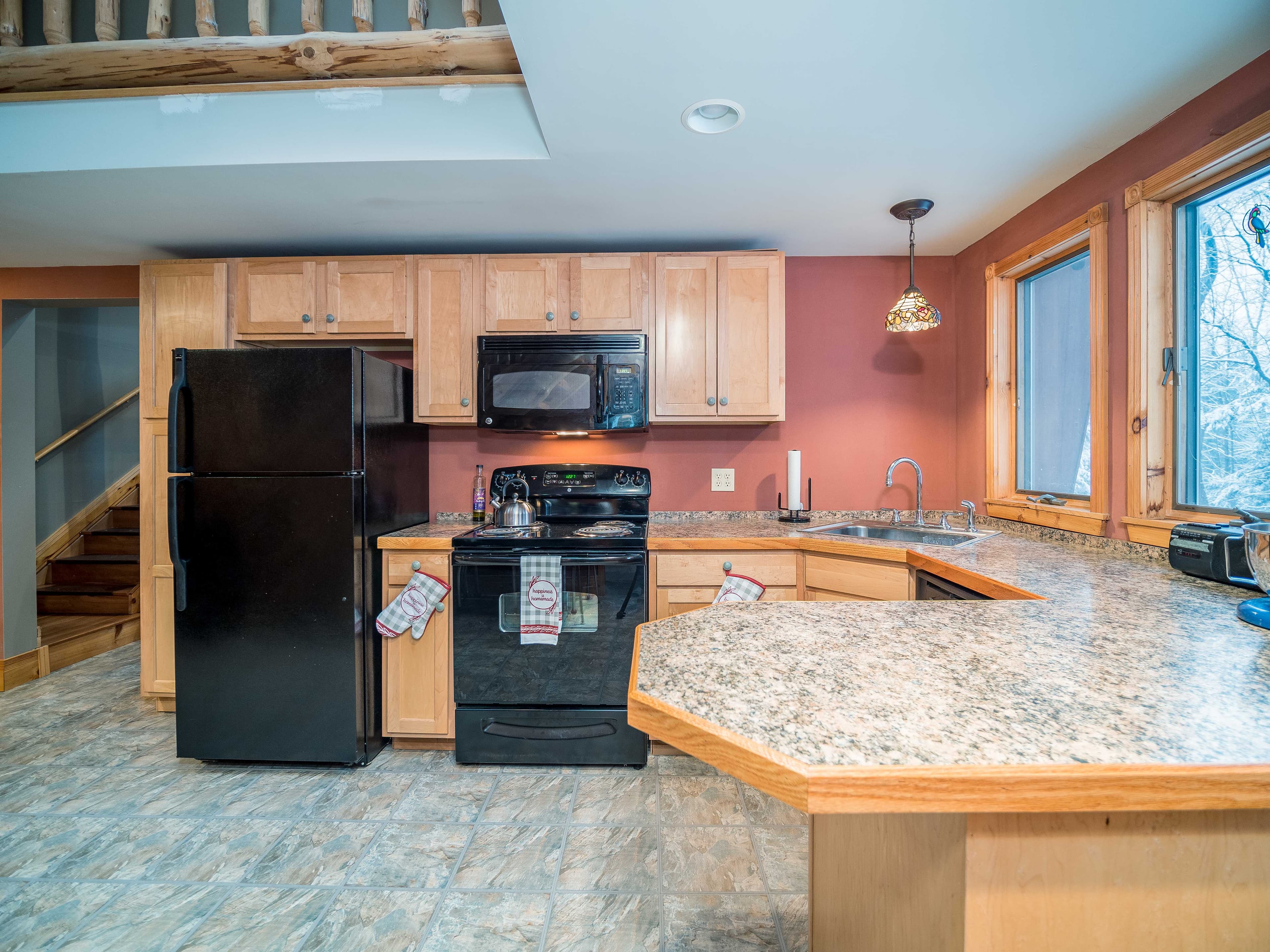 The lodge kitchen with maple cabinets, a breakfast bar, and windows into the snowy woods